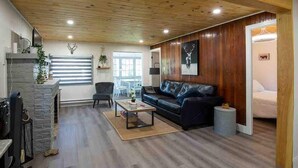 Una sala moderna con chimenea de piedra, un sofá de cuero negro y una zona de comedor con mesa de piedra.