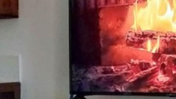 A television mounted on a wall with a fire scene displayed. - Cabaña Silva (Tocoa)