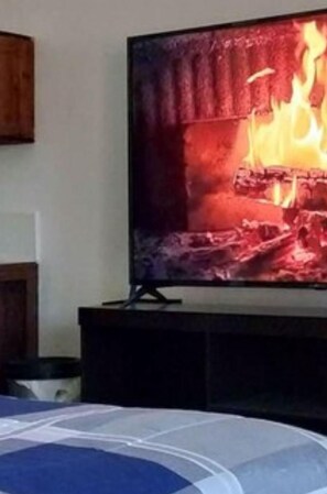 Un televisor montado en la pared mostrando una escena de fuego.