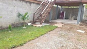A courtyard with a concrete wall, a gravel path, and two small trees. - Cabaña Silva (Tocoa)