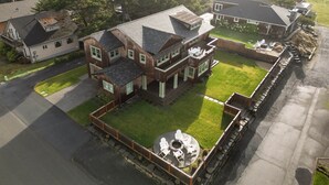 A large, multi-story house with a well-maintained lawn and a patio area with outdoor furniture. - The Ridge - Gearhart, OR (Gearhart)