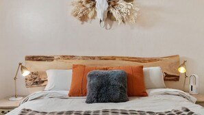 Un letto con testiera in legno, due cuscini e un cuscino soffice, con un elemento decorativo a parete.