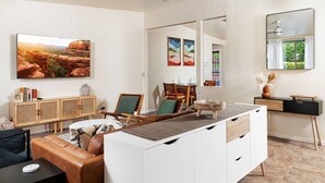 Un soggiorno moderno con un divano, una zona pranzo con sedie, un mobile bianco e un grande quadro appeso al muro.