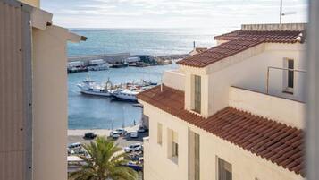 Une vue sur la côte depuis un balcon donnant sur une marina, avec des bateaux et un ciel dégagé.