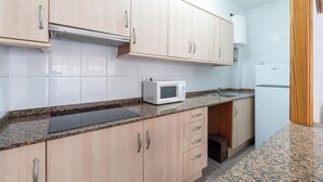 Eine Küche mit hellen Holzschränken, einer weißen Mikrowelle und einem Kühlschrank.