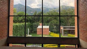 Une pièce dotée d’une grande fenêtre donnant sur un jardin luxuriant et sur des montagnes lointaines.