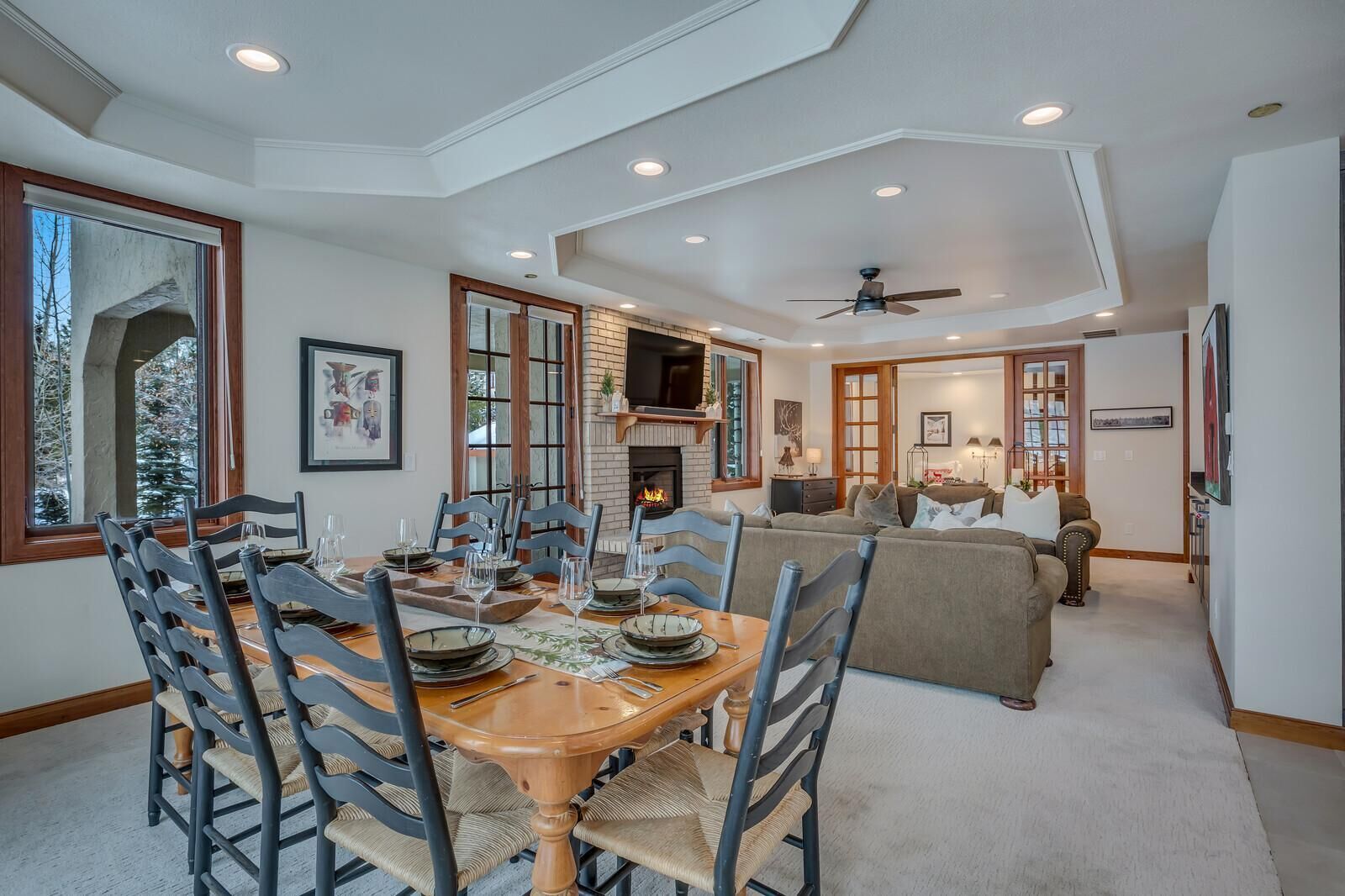 A dining area with a wooden table and chairs, a fireplace, and a sofa in the background.