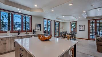 Una cocina moderna con una isla grande, armarios de madera y ventanas amplias que ofrecen vistas a un paisaje nevado.