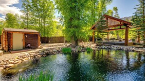 Eine rustikale Holzhütte mit einem kleinen Teich, umgeben von Bäumen und einer Holzterrasse.