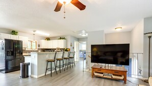 A modern kitchen with a refrigerator, a trash can, and a bar area with stools. - Fire Pit & Dock: Lake of the Ozarks Retreat! (Roach)
