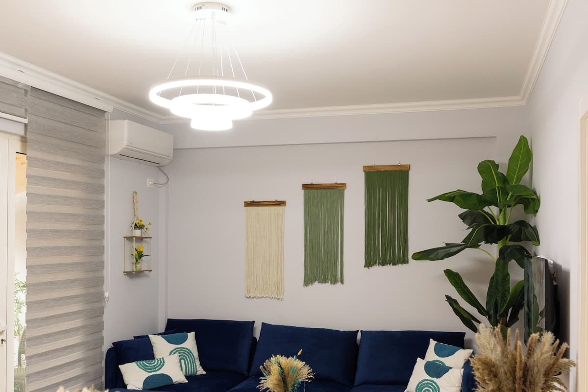 A modern living room with a blue sofa, wooden coffee table, and a dining area with a wooden table and chairs.