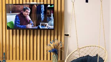 Una sala moderna con un televisor montado en una pared de paneles de madera, un sillón colgante y un tapiz redondo tejido.