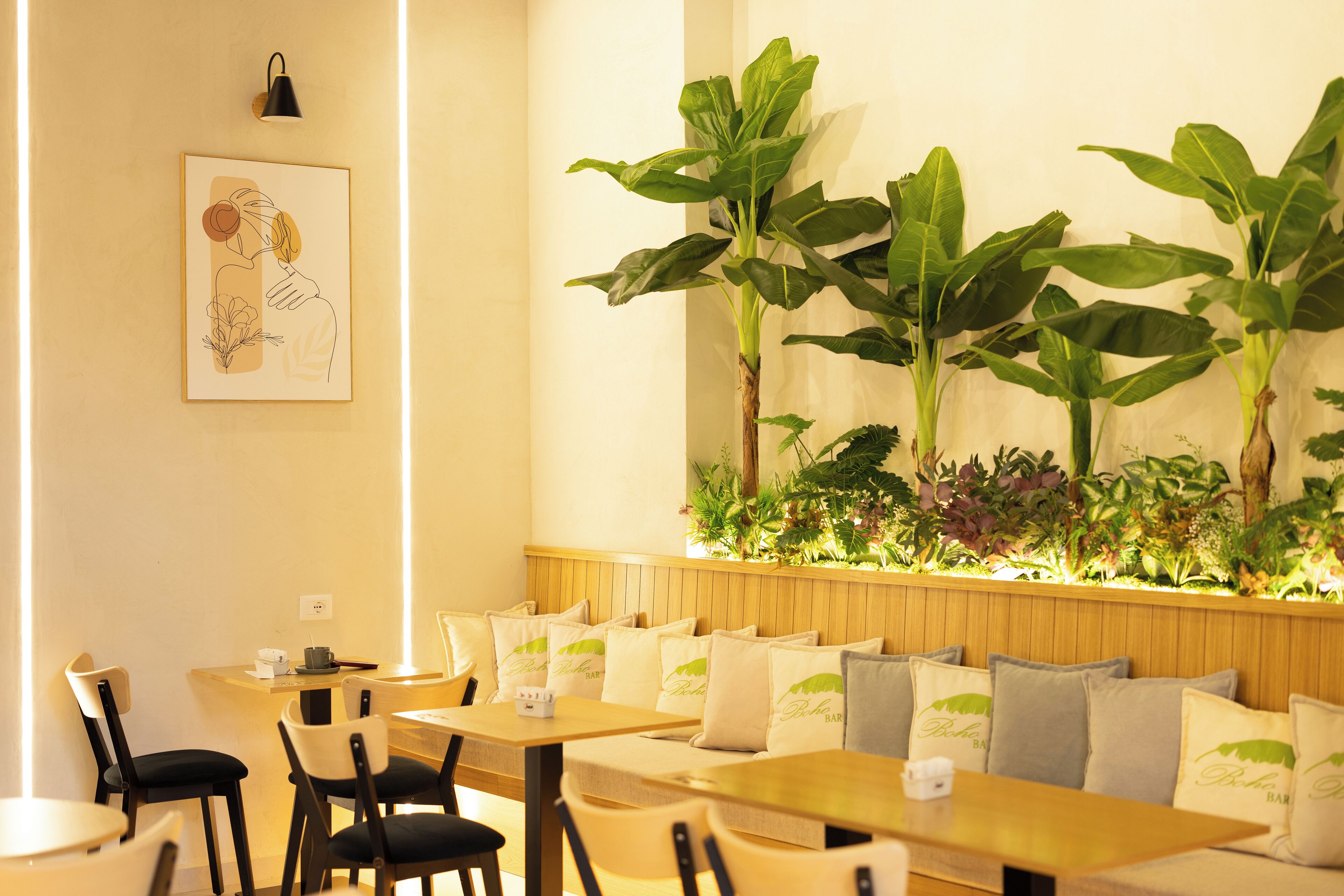 A restaurant with wooden tables and chairs, a wall-mounted light fixture, and a large potted plant.