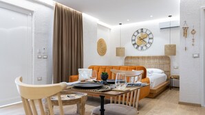 A modern, well-lit room with a dining table set for two, a sofa, and a bed with a headboard. -  Boho Central Apartment (Tirana)