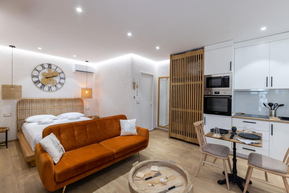 A modern room with a bed, orange sofa, dining table, and a kitchen area.