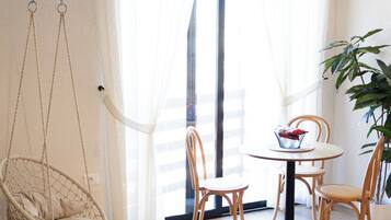 A room with a wicker chair, a round table, and a hanging light fixture.