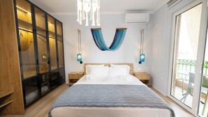 A bedroom with a large bed, a wardrobe, a chandelier, and a view of the outside. -  Boho Central Apartment (Tirana)
