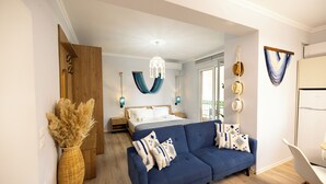 A modern bedroom with a bed, a blue sofa, and a wicker vase. -  Boho Central Apartment (Tirana)