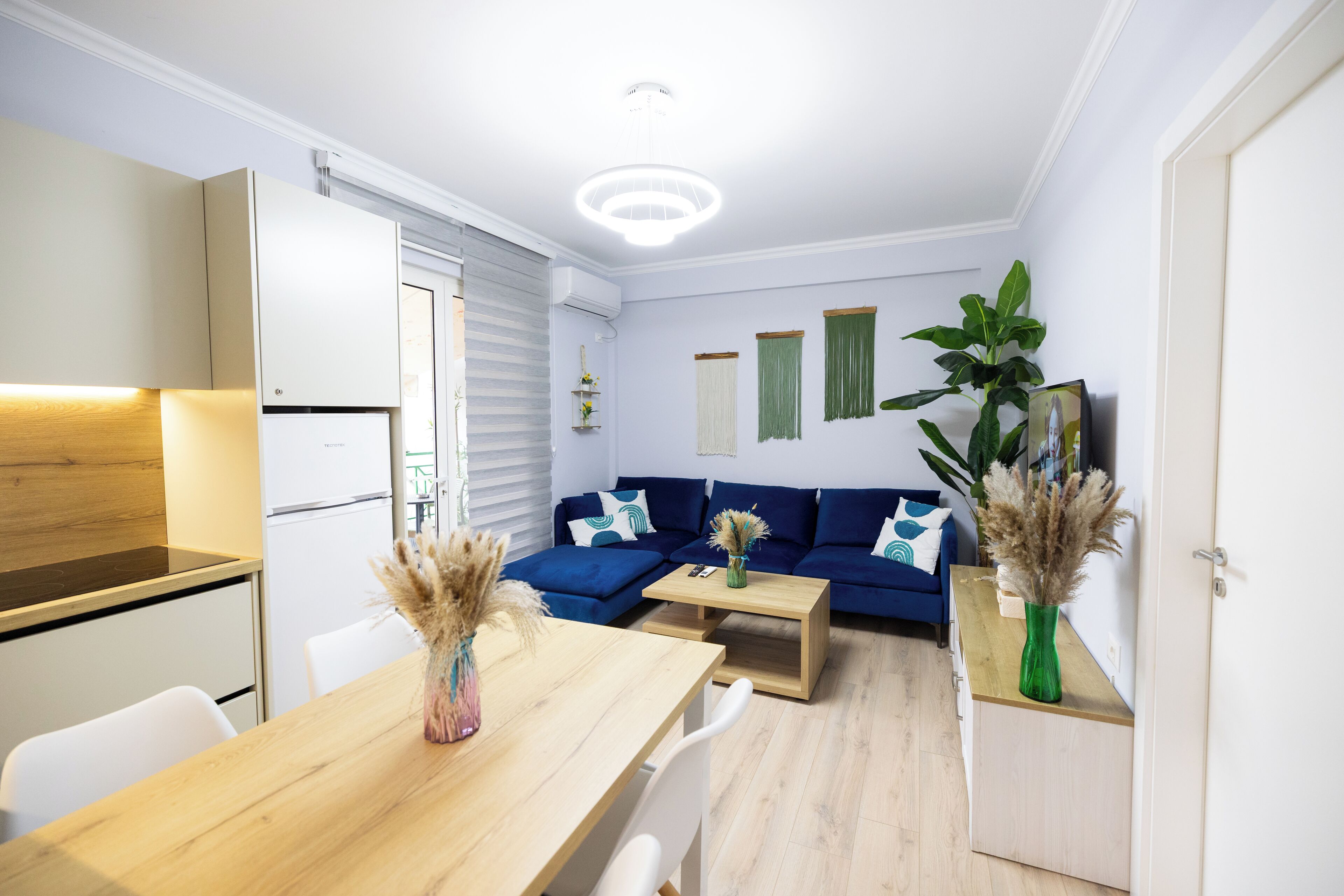 A modern living space with a dining area, a sofa set, and a kitchen.