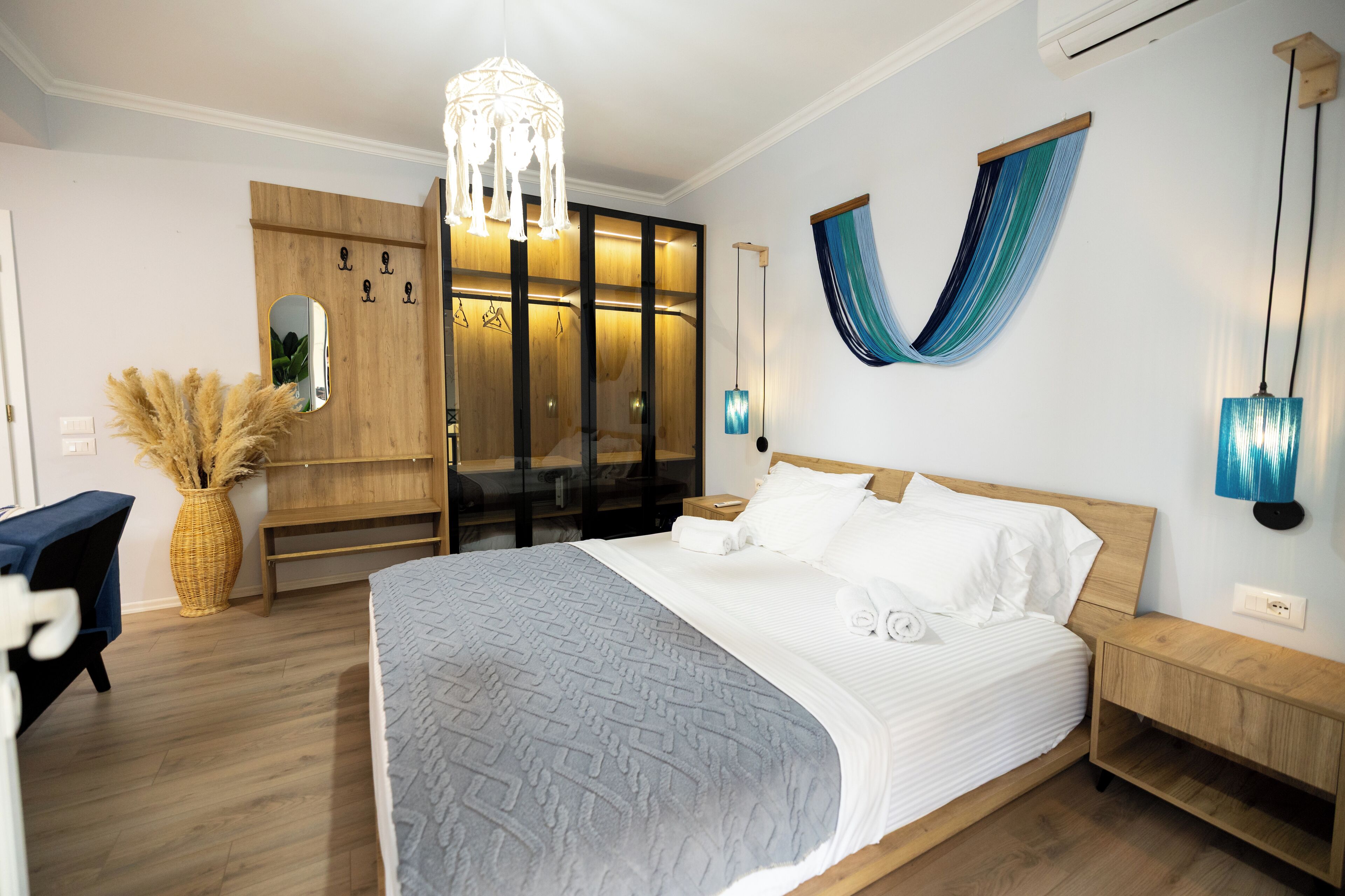 Quarto moderno com cama grande, armário de madeira e rede suspensa.