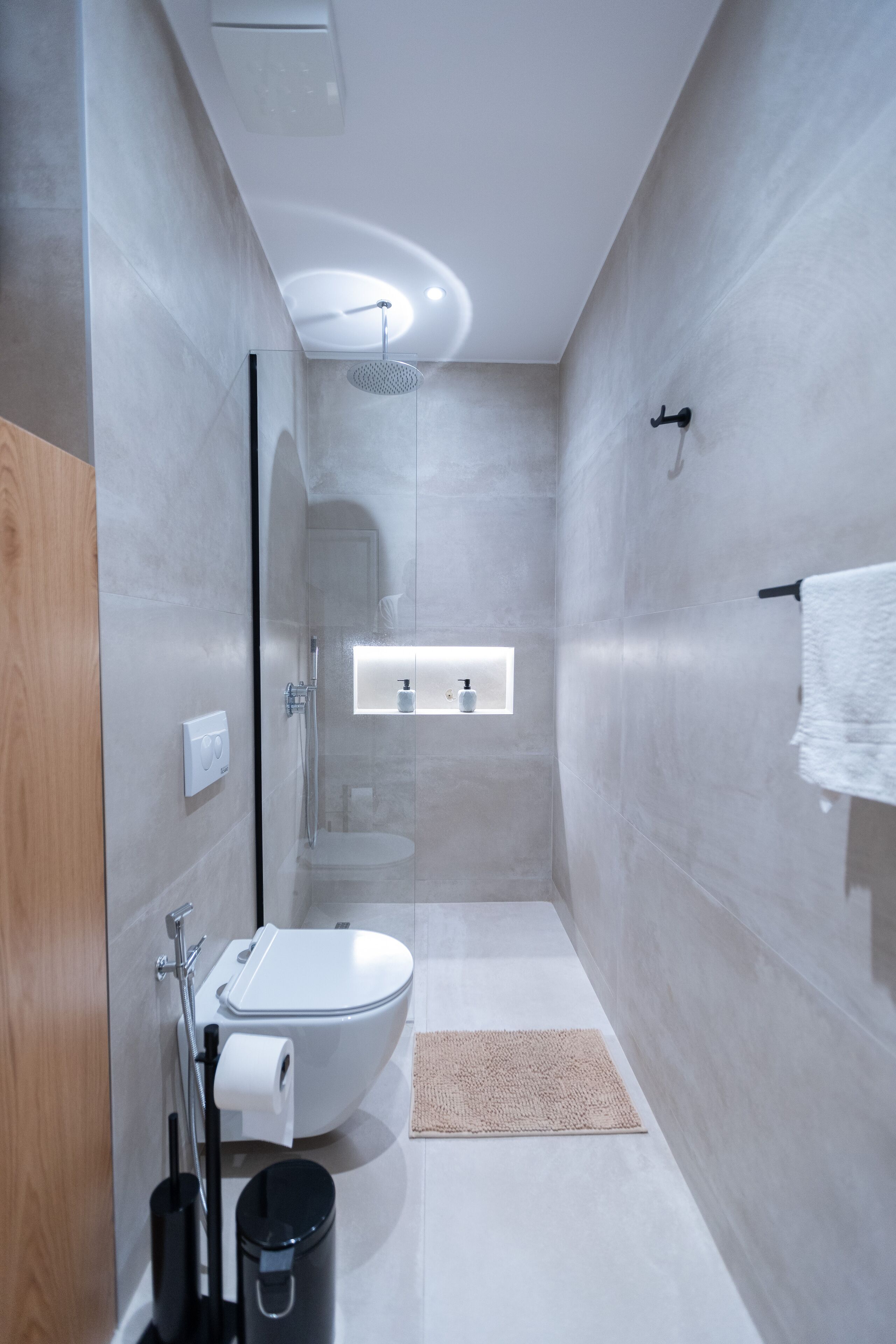 A modern bathroom with a glass-enclosed shower, a toilet, and a sink.