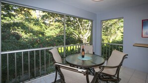 Ein Balkon mit Tisch und Stühlen, einer Weinflasche und einem Bild an der Wand.