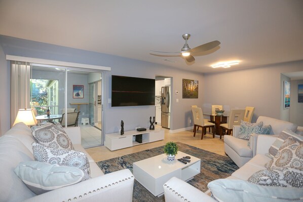 A modern living room with a sofa set, coffee table, and a flat-screen TV.
