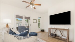 Una sala de estar con sofá, sillón y televisión sobre un mueble de madera.