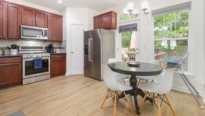 Una cocina moderna con armarios de madera, electrodomésticos de acero inoxidable y un comedor con una mesa redonda y sillas.