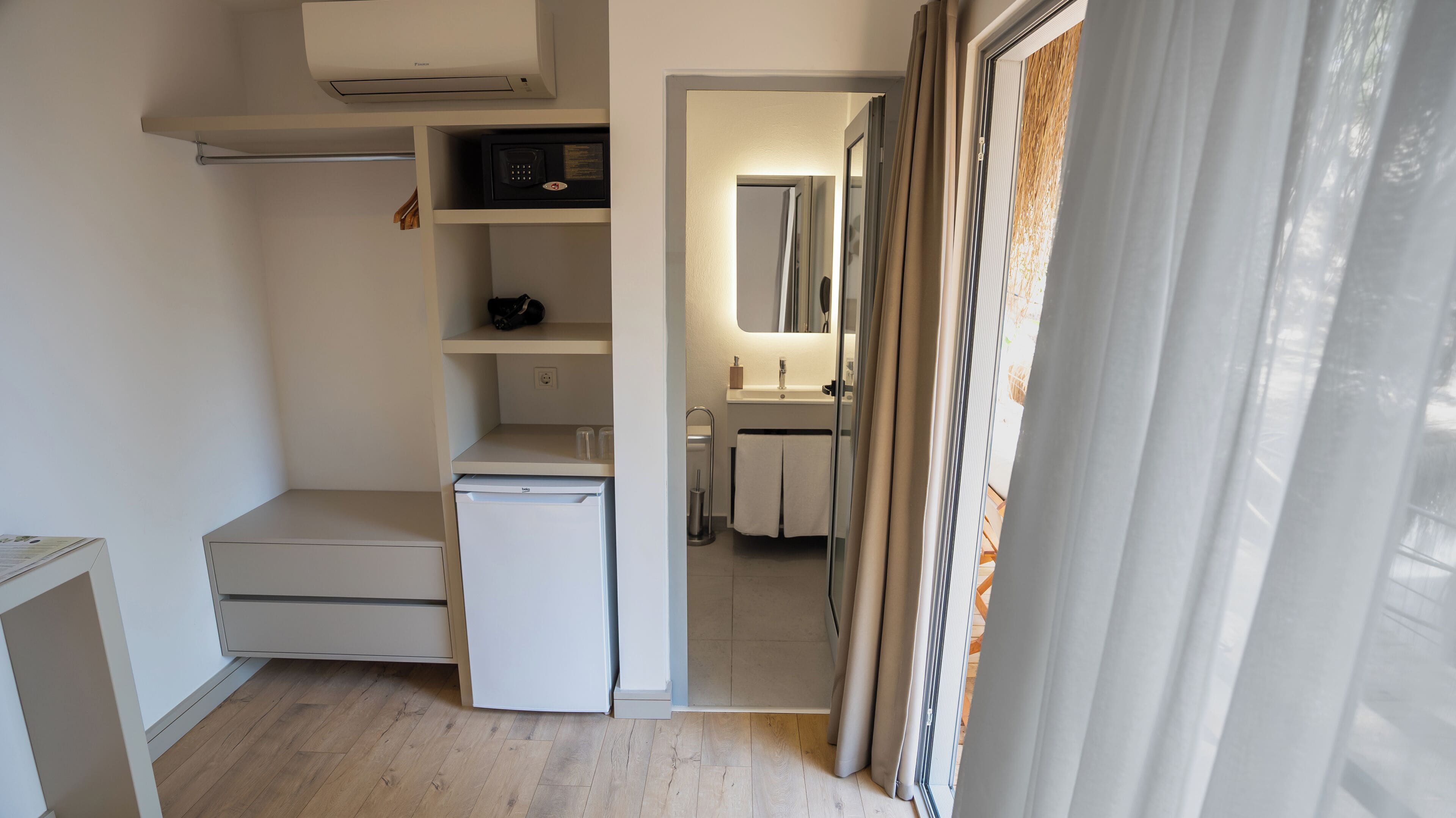Una cocina compacta con microondas integrado, un refrigerador pequeño y un lavamanos.
