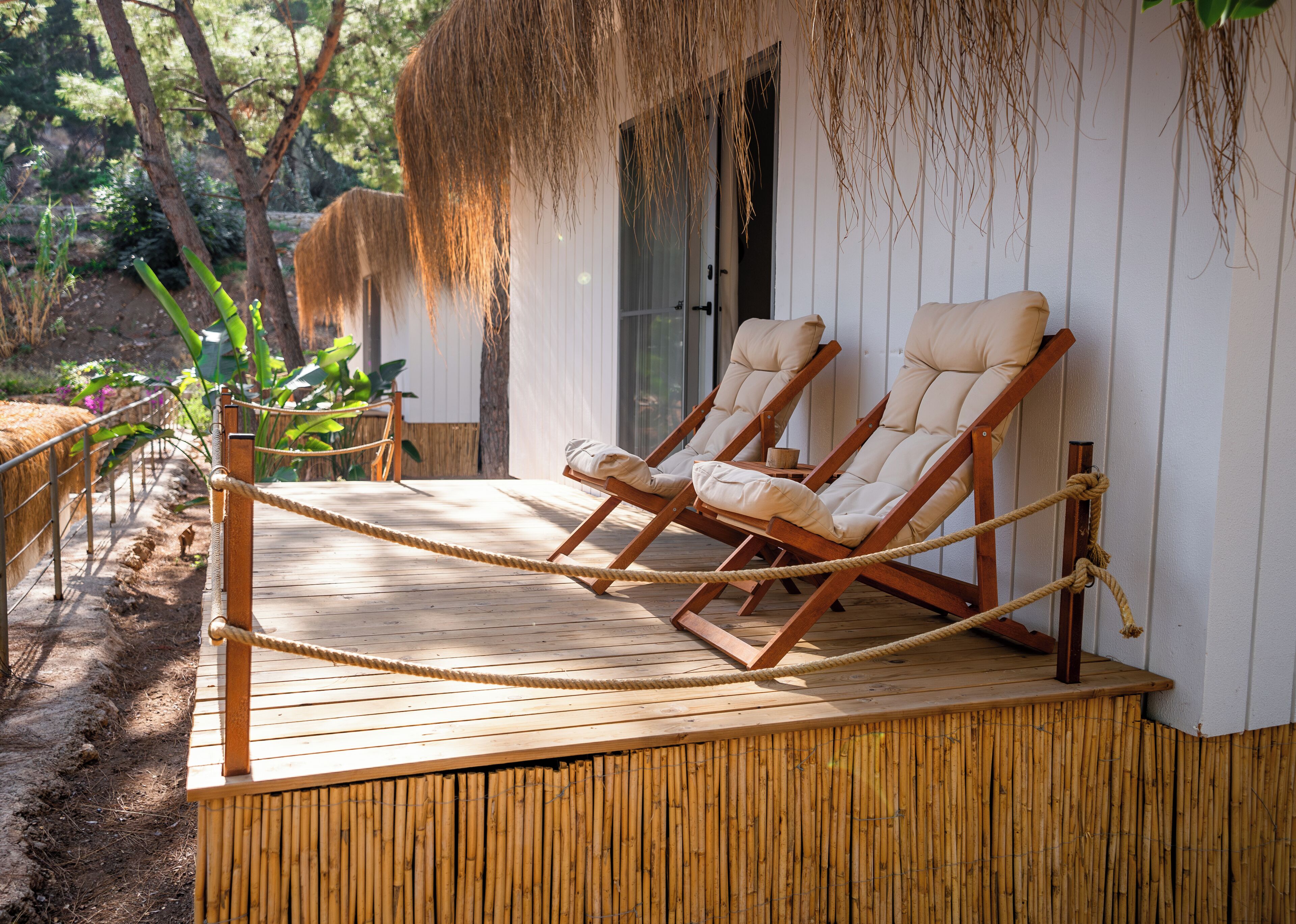A wooden deck with two lounge chairs and a rope barrier.