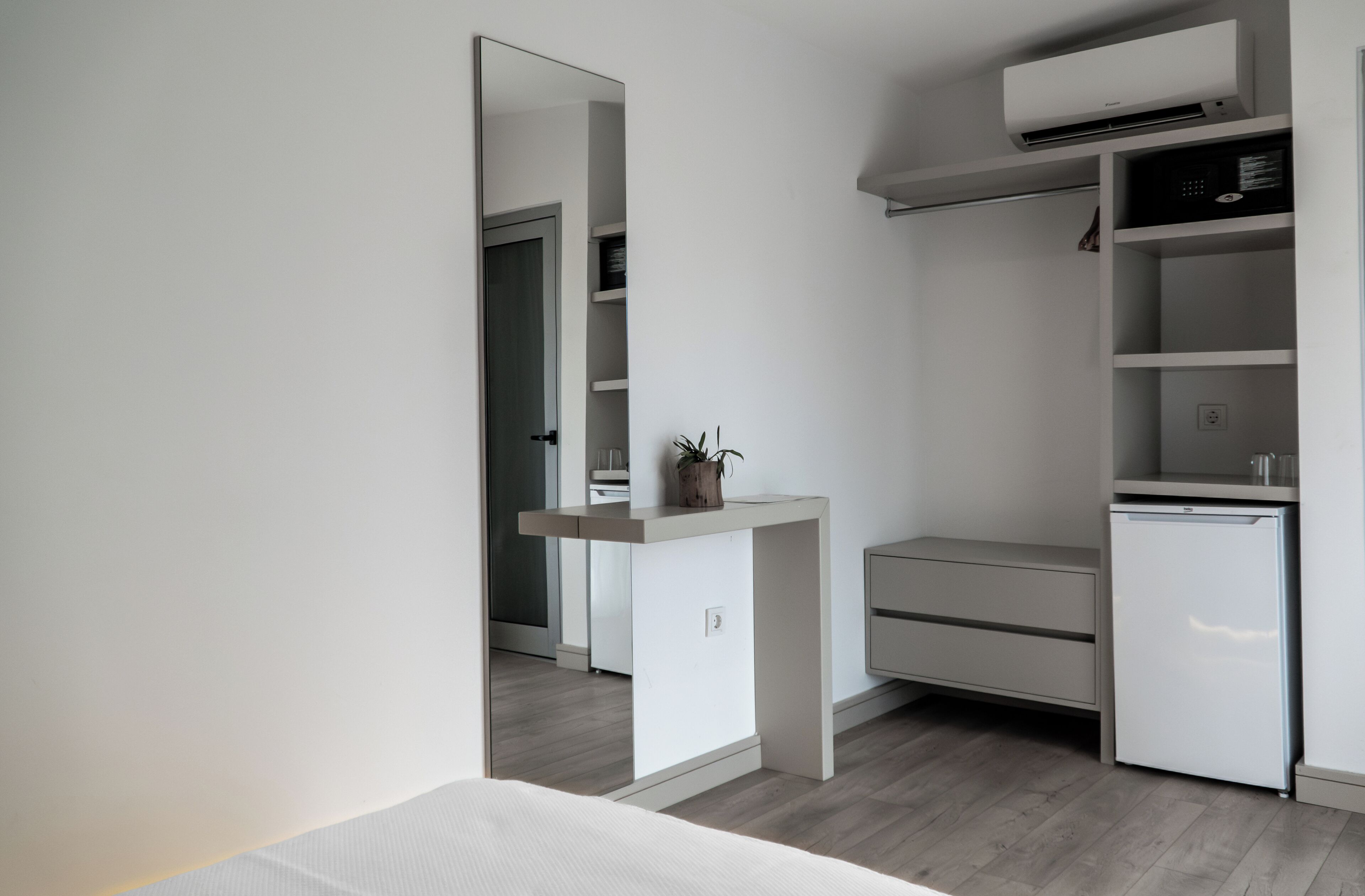 A compact, modern kitchenette with a built-in refrigerator, a small countertop, and a wall-mounted air conditioner.