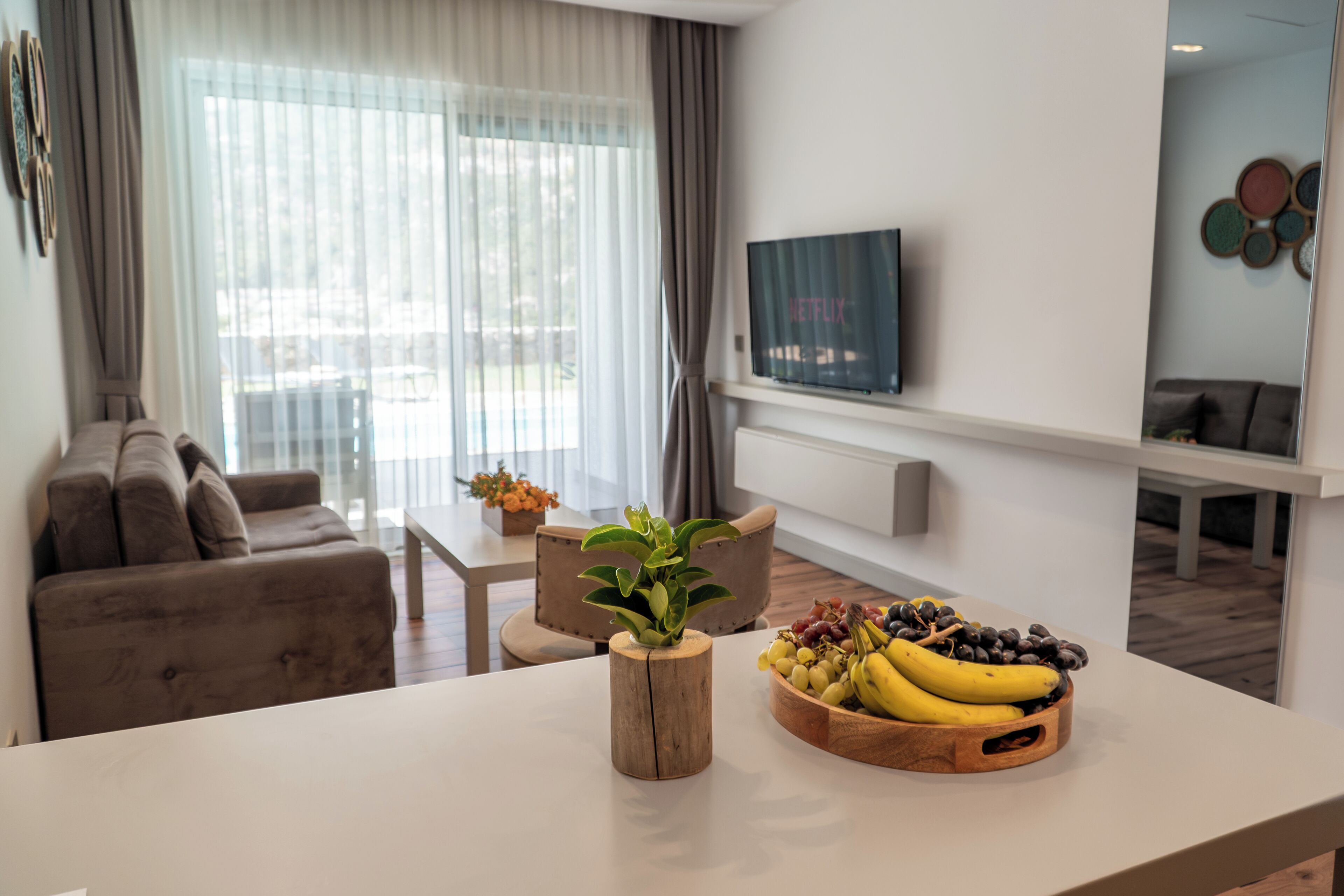 A modern living room with a sofa, a coffee table, a plant, and a fruit bowl.