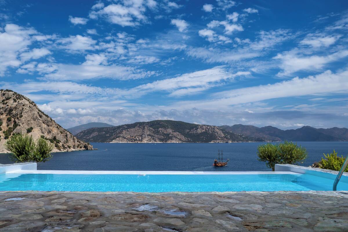 A pool with a view of the sea and mountains.