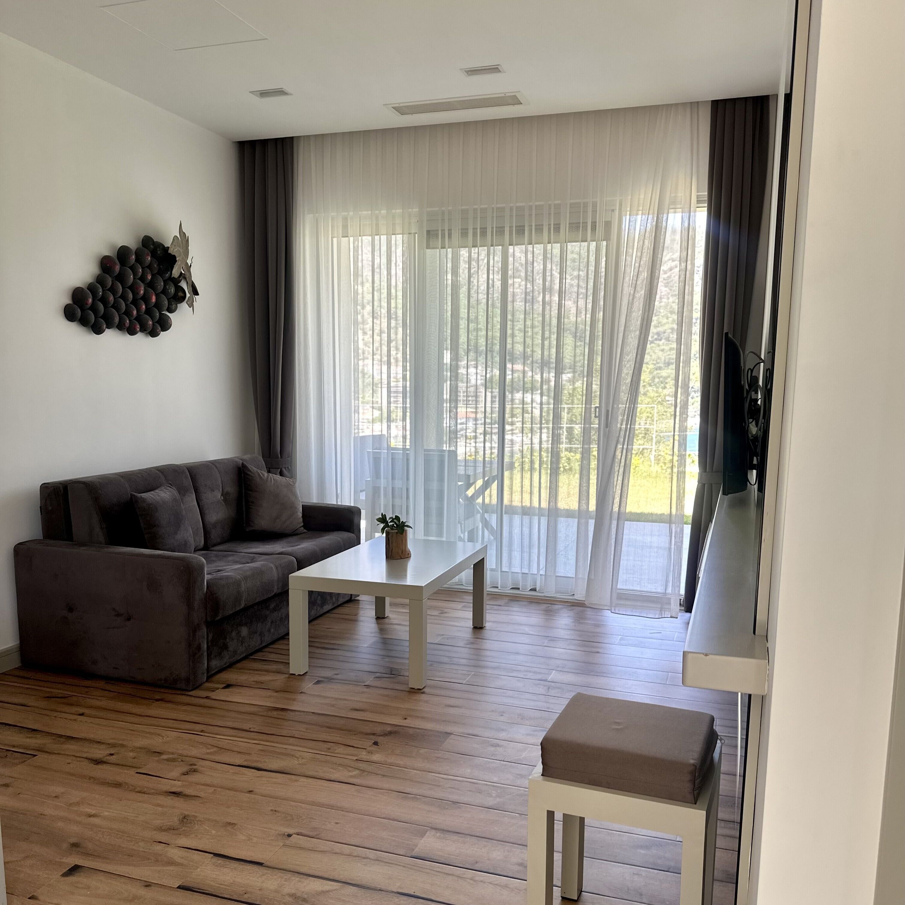 A modern living room with a dark brown sofa, a white coffee table, and a small white table with a cushion.