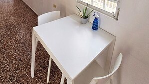Ein weißer Tisch mit zwei Stühlen, einem Blumentopf und einer Sprühflasche.