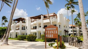 A white multi-story hotel with balconies, palm trees, and a sign reading "Stanza Mare". - Just  few steps from Beach, Enjoy a Sunrise in this Wonderful place (Punta Cana)
