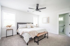 Cozy retreat with a single bed, bedside table, and bench, complete with a ceiling fan and window.