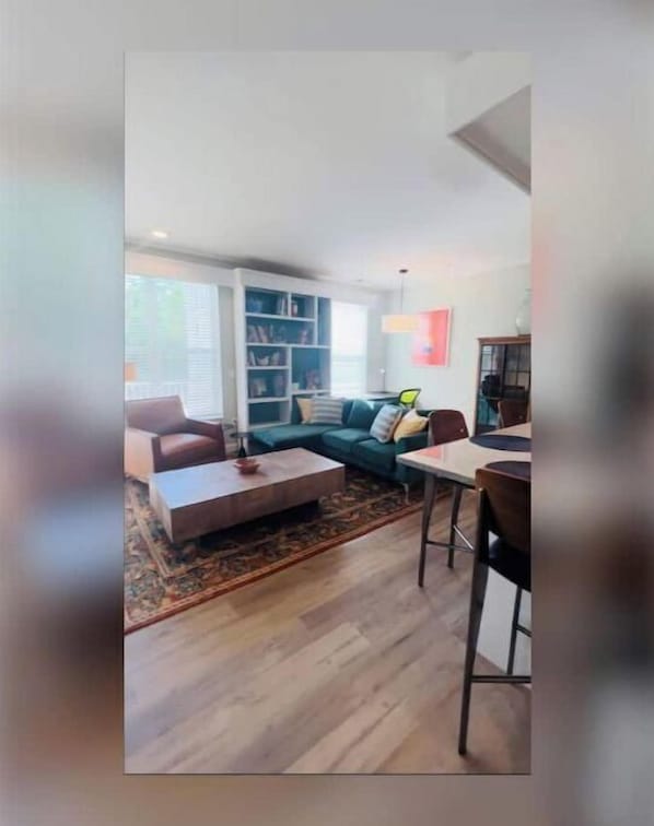 A living room with a sofa, coffee table, and a dining area with chairs and a table. - Waterford, CT - Beautifully furnished 1Bedroom/1Bath 864sf Apartment (Waterford)