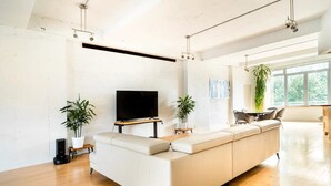 Ett modernt vardagsrum med en stor, L-formad soffa, en platt-TV och två krukväxter.