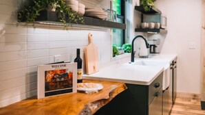 A modern kitchen with white subway tiles, a wooden countertop, and a built-in dishwasher. - The Treehouse @Brandywine Grove (Sugarcreek)