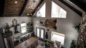 Una cocina amplia con techo alto, vigas de madera y una lámpara colgante.