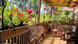 A covered outdoor area with a wooden deck, chairs, and potted plants.