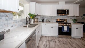 A modern kitchen with white cabinets, a built-in microwave, a stove, and a sink. - Fallbrook's Finest Hideaway Casa - Pool, Game Rm (Fallbrook)