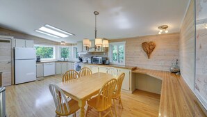 A modern kitchen with wooden flooring, white cabinets, a central island, and a chandelier. - Cozy Langley Retreat: Water Views & Beach Access (Langley)