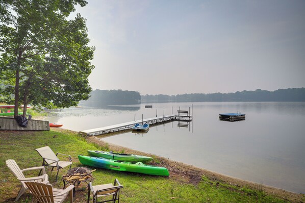 A lakeside dock with kayaks, chairs, and a fire pit. - Lakefront Sister Lakes Vacation Rental w/ Dock! (Dowagiac)