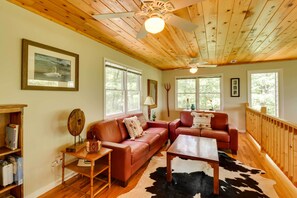 A cozy living room with a wooden ceiling, two leather sofas, a coffee table, and a cowhide rug. - Spacious Georgia Escape w/ Fireplace, Deck & Grill (Lakemont)