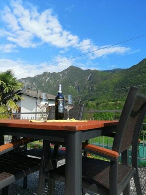 An outdoor dining area with a table and chairs, a bottle of wine, and a glass on the table. - Da Rita - Two Bedroom Apartment (Crone)