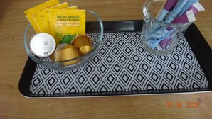 Ein Tablett mit einer Glaskugel, einem Metallsieb, gelben Karten sowie einem Glas mit Trinkhalmen und einem violetten Gegenstand.