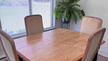 Una mesa de comedor con cuatro sillas, una planta en maceta y una ventana con persianas.